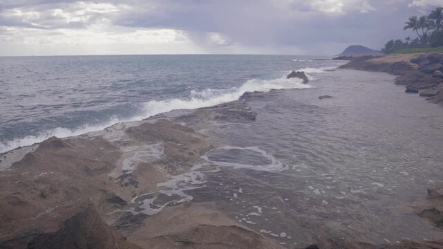Small wave overflow crashing ripple into beach ocean tidepool sea shore, cloudy sunset nature beauty island background. North Shore, Hawaii.