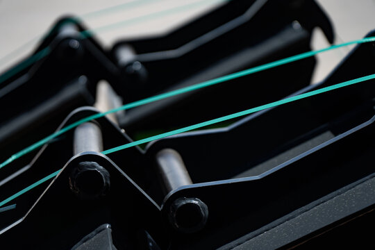 Industrial cargo packaging details showing parallel green plastic straps binding manufactured black metallic equipment