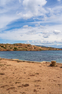 View of the historic Batterie di Punta Rossa fortifications overlooking the turquoise sea and rocky coastline in La Maddalena, Sardegna, Italy.