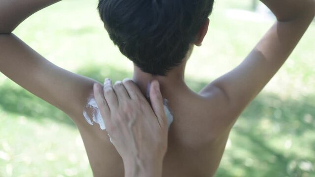 Mother applying sunscreen on son's back for uv protection, close-up of skin care routine for sunburn prevention and healthy tanning during summer vacation outdoors