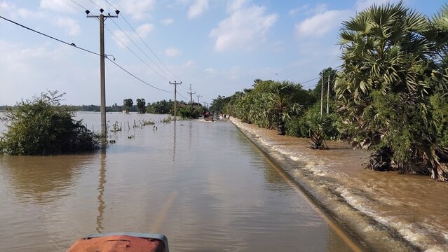 Flooded Rural Road with Overflown Water and Utility Poles in Cloudy Weather