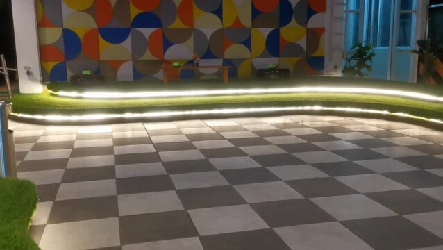 Modern outdoor lounge area with checkered pavement and decorative lighting