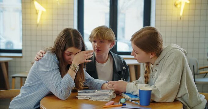 Friends comforting crying teenage girl during emotional conversation