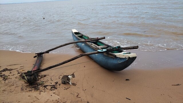 Traditional outrigger canoe resting on a sandy tropical beach at low tide