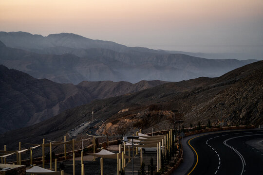 View of the winding mountain road near Arashan Lake with arid rocky slopes and sunshades in the foreground in Pop District, Namangan Region, Uzbekistan.