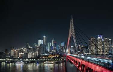 Fototapeta premium The nocturnal skyline of Chongqing unfolds from the Qiansimen Bridge, striking a perfect harmony between architectural power and graceful illumination. Dominating the foreground, the magnificent cable