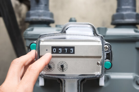 Natural gas line meter inspected by gas technician. Close up. Residential multi-dwelling building or home. Outdoor meter measuring displaying the actual usage number in cubic feet. Selective focus.