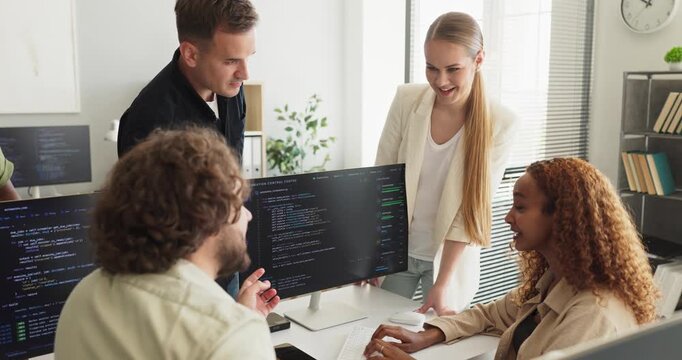 Developers team lead code review in office. Programmers discuss updates at monitors as a colleague explains tasks and aligns collaboration for the next sprint. Teamwork gets results done fast.