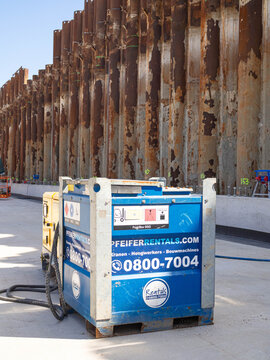 Pfeifer Rentals fuel box and power equipment beside rusty sheet pile retaining wall at A9 road construction site for Amsterdam highway ring road works, 25 June 2026, Amstelveen, The Netherlands