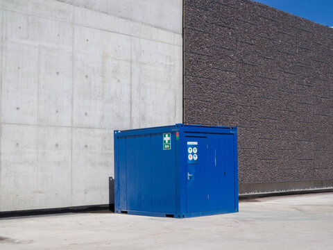 Blue first aid site container beside concrete wall and gabion noise barrier at A9 Amsterdam ring road construction area for safety and infrastructure, 25 June 2026, Amstelveen, The Netherlands