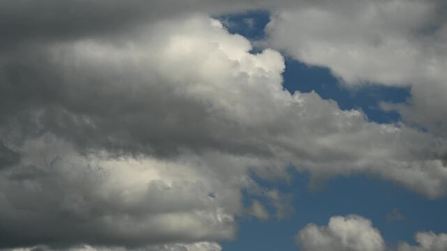 Timelapse of quickly moving summer cumulus storm clouds churn through a blue sky