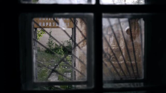 Street view through a grated window in an abandoned house. The atmosphere of desolation and loneliness