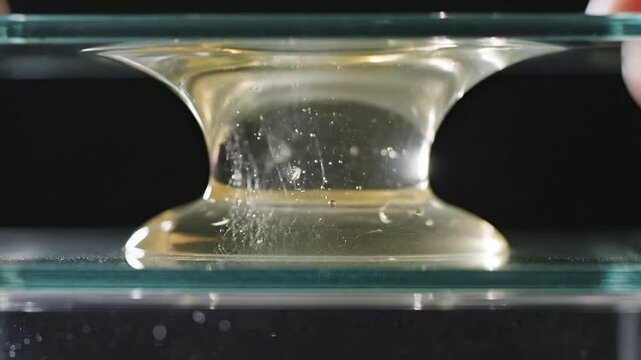 Close-Up Experiment Demonstrating Elastic Properties of Transparent Material Between Two Glass Plates Being Pulled Apart
