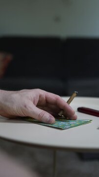 Vertical screen Hand holding cigarette above lottery scratch ticket highlighting gambling addiction smoking habit hope for fast money financial risk and unhealthy lifestyle