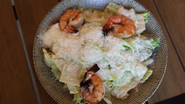 Fresh Caesar salad with grilled shrimp crisp romaine lettuce creamy dressing and grated parmesan served in a restaurant as a healthy seafood meal