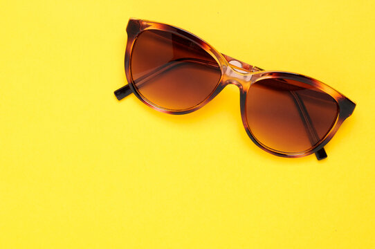 Tortoiseshell sunglasses on plain yellow background with copy space