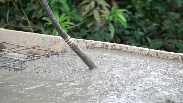 Using Mechanical Concrete Vibrator Machine on Poured Wet Cement Close Up. Workers Compacting Liquid Concrete Mix with Vibrator Tool at Construction Site. 