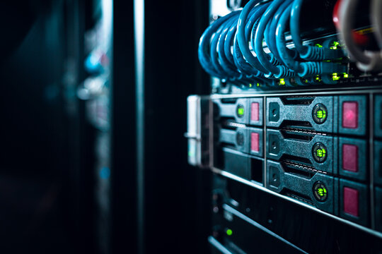 View of server rack with blue ethernet cables and glowing green status lights in a data center in Los Angeles, California, United States.