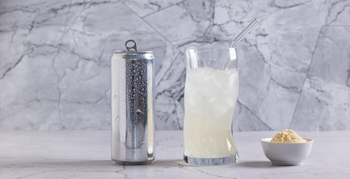 Carbonated protein drink in a glass and protein powder in a bowl on a table web banner