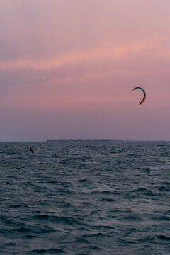 View of a kitesurfer gliding across the sea during a vibrant sunset in Dubai, Dubai, United Arab Emirates.