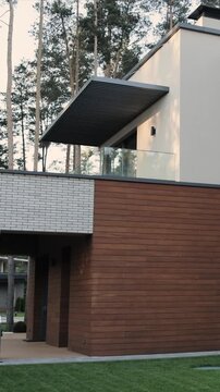 Vertical video. Contemporary balcony featuring slatted roof and glass railing on modern home.