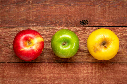 red, green and gold apples on weathered rustic barn wood table