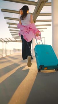 Caucasian woman pulling a suitcase and running, late for flight. 