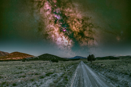 View of the Milky Way galaxy stretching over a dirt road in the desert landscape along the historic Pony Express Trail near Dugway, Utah, United States.