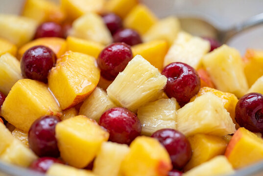 Macro close up of colorful mixed fruit salad with pineapple and cherries