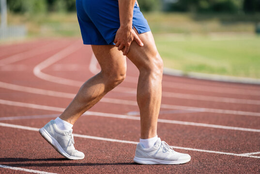 Man holding his leg with muscle pain on an outdoor running track