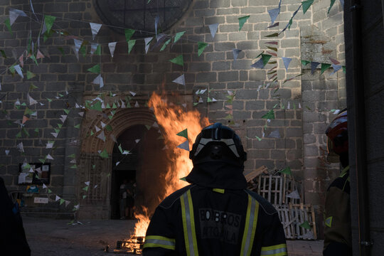 Traditional midsummer bonfire burning brightly outside the historic Church of San Juan Bautista during the Night of San Juan festival in Avila, Castile and Leon, Spain.
