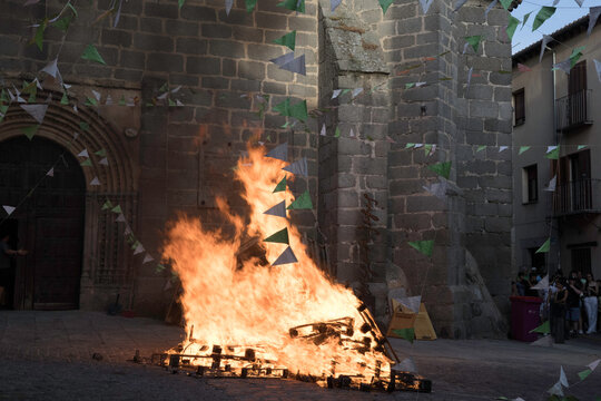 Traditional midsummer bonfire burning brightly outside the historic Church of San Juan Bautista during the Night of San Juan festival in Avila, Castile and Leon, Spain.
