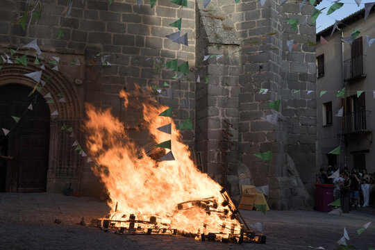 Traditional midsummer bonfire burning brightly outside the historic Church of San Juan Bautista during the Night of San Juan festival in Avila, Castile and Leon, Spain.