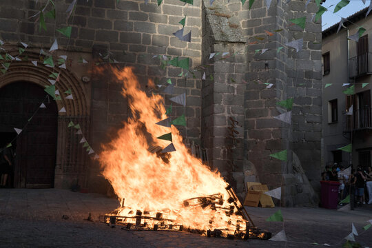 Traditional midsummer bonfire burning brightly outside the historic Church of San Juan Bautista during the Night of San Juan festival in Avila, Castile and Leon, Spain.