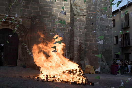 Traditional midsummer bonfire burning brightly outside the historic Church of San Juan Bautista during the Night of San Juan festival in Avila, Castile and Leon, Spain.