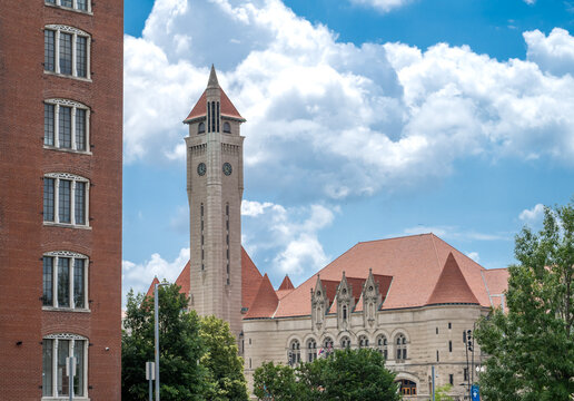 View of the historic clock tower and Romanesque architecture of St. Louis Union Station under a bright blue sky with fluffy white clouds in St. Louis, Missouri, United States.