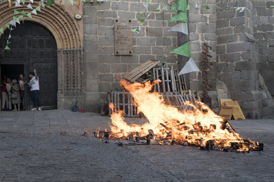 Traditional midsummer bonfire burning brightly outside the historic Church of San Juan Bautista during the Night of San Juan festival in Avila, Castile and Leon, Spain.