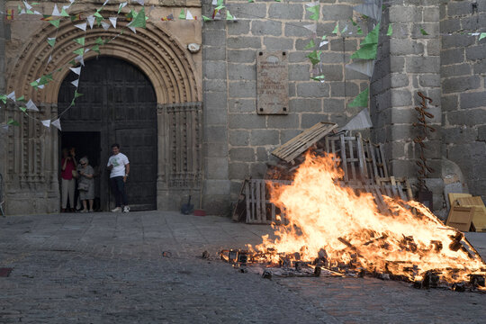 Traditional midsummer bonfire burning brightly outside the historic Church of San Juan Bautista during the Night of San Juan festival in Avila, Castile and Leon, Spain.