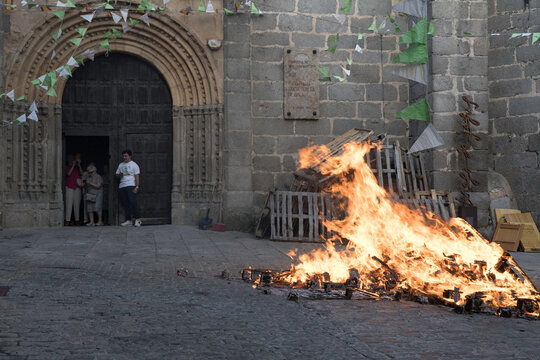 Traditional midsummer bonfire burning brightly outside the historic Church of San Juan Bautista during the Night of San Juan festival in Avila, Castile and Leon, Spain.