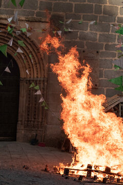Traditional midsummer bonfire burning brightly outside the historic Church of San Juan Bautista during the Night of San Juan festival in Avila, Castile and Leon, Spain.