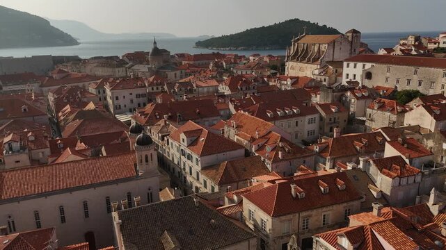 Aerial push forward over Dubrovnik roofs past Orthodox Church to Cathedral and St Ignatius 4K