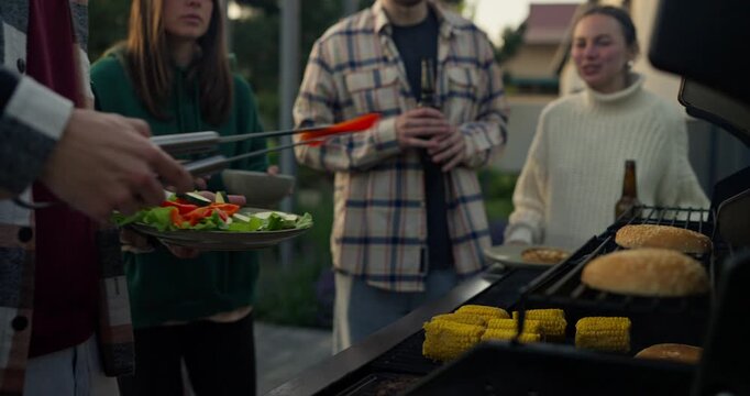 Casual backyard barbecue gathering with friends cooking outdoors