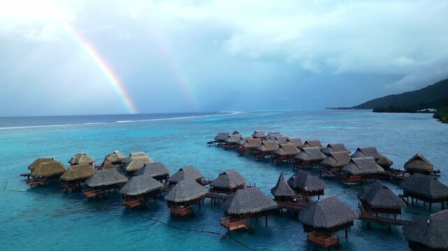 Overwater bungalows at tropical luxury resort with double rainbow. Moorea island, french polinesia