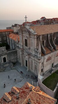 Vertical aerial orbit of St Ignatius Church facade in Dubrovnik old town at twilight dusk 4K