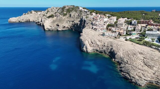 Aerial view of the rocky cliffs and Mediterranean sea surrounding the Cala Agulla beach area in Balearic Islands, Balearic Islands, Spain.