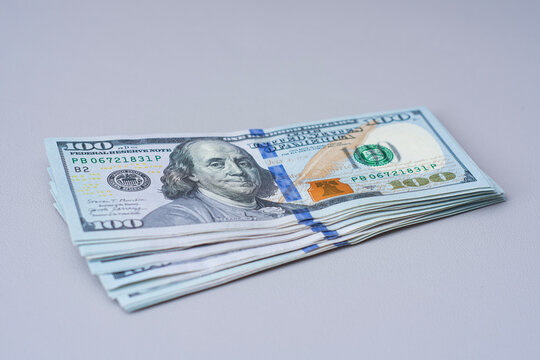 Stack of one hundred US dollar banknotes on neutral background. Cash savings, personal finance, investment, business payment and wealth management concept for banking and financial planning.