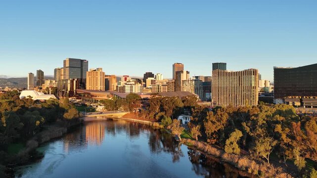 River Torrens, Adelaide City, South Australia &ndash; 4K aerial drone footage of urban river, CBD skyline, Towers, Convention Centre, Elder Park, city bridges and golden sunset cityscape.