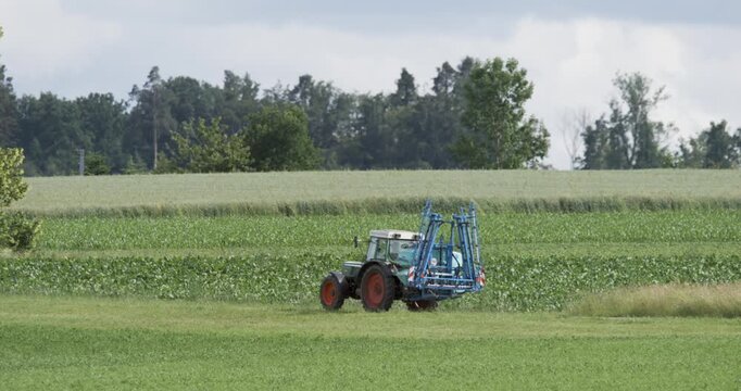 Farm Tractor Spraying Crops in a Vibrant Green Field