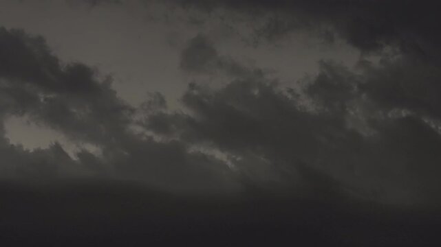 Moody night storm with flashing lightning inside thick clouds