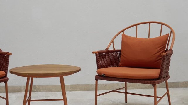 Shot of a vibrant orange chair and a small round table in a cozy setting
